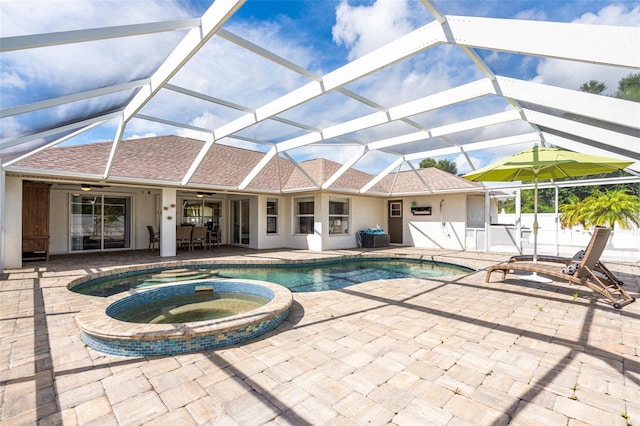 view of swimming pool featuring glass enclosure, a patio, ceiling fan, and a pool with connected hot tub