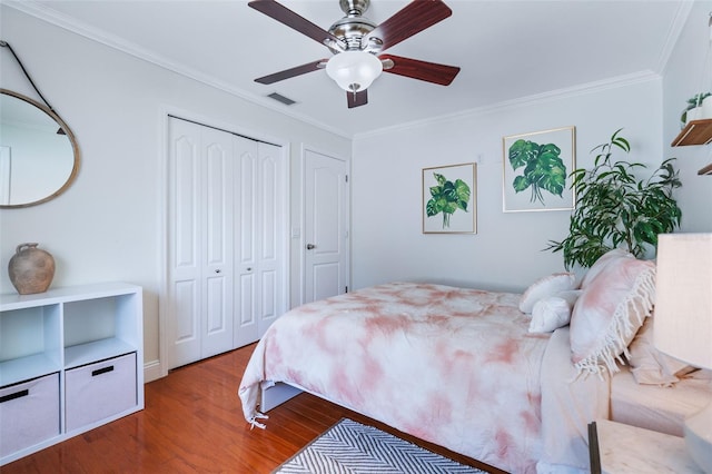 bedroom with visible vents, ornamental molding, wood finished floors, a closet, and a ceiling fan