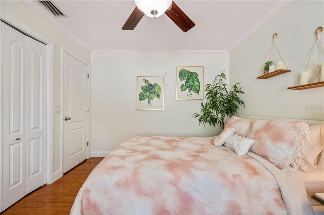 bedroom with ceiling fan, ornamental molding, a closet, and hardwood / wood-style flooring