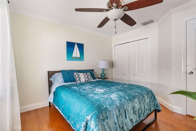 bedroom featuring ornamental molding, a closet, ceiling fan, and light hardwood / wood-style floors