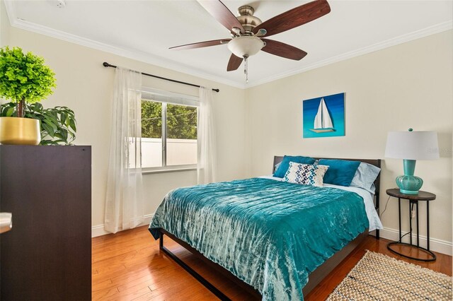 bedroom with crown molding, wood-type flooring, and ceiling fan