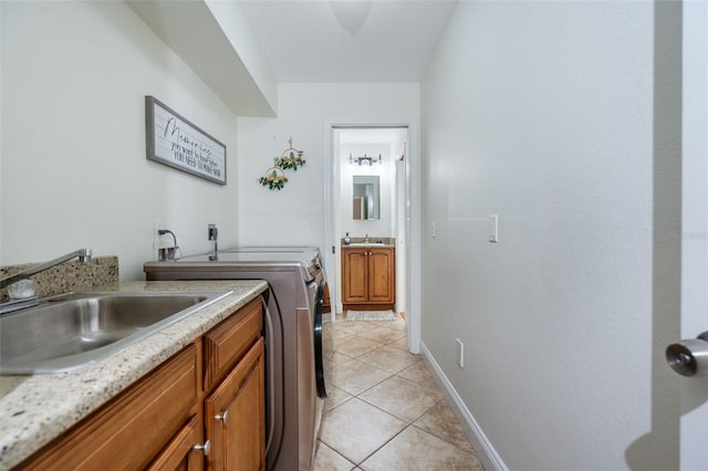 washroom featuring light tile patterned floors, cabinets, washing machine and clothes dryer, and sink