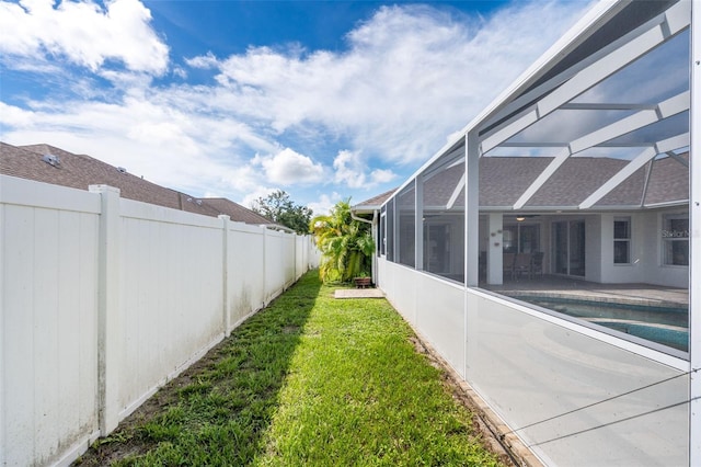 view of yard featuring glass enclosure, a fenced in pool, and a patio area