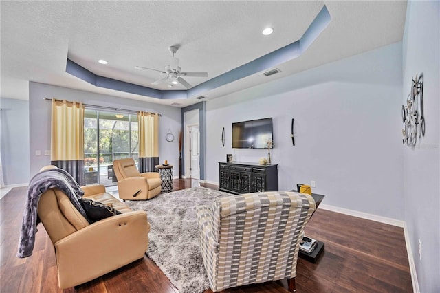 living room featuring a tray ceiling, ceiling fan, and dark hardwood / wood-style floors