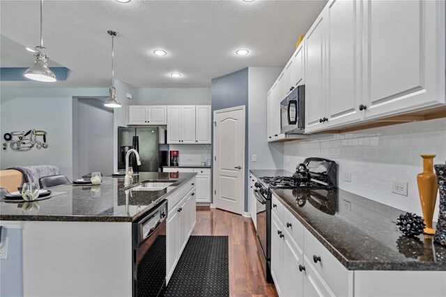 kitchen featuring white cabinetry, decorative light fixtures, black appliances, sink, and a center island with sink