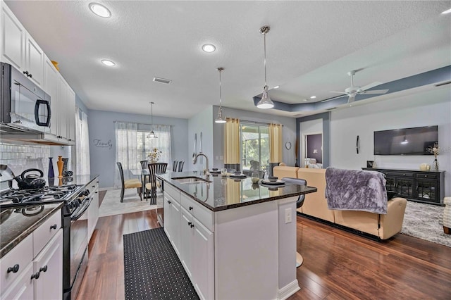 kitchen with range with gas cooktop, dark hardwood / wood-style flooring, an island with sink, ceiling fan, and sink