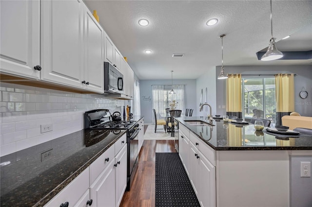 kitchen with a center island with sink, black appliances, dark wood-type flooring, sink, and a wealth of natural light