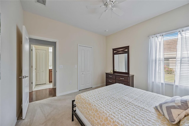 bedroom with light colored carpet, ceiling fan, and a closet