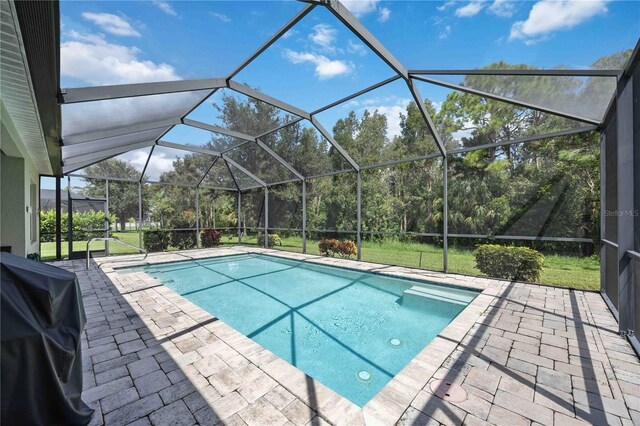 view of pool featuring a lawn, a lanai, and a patio