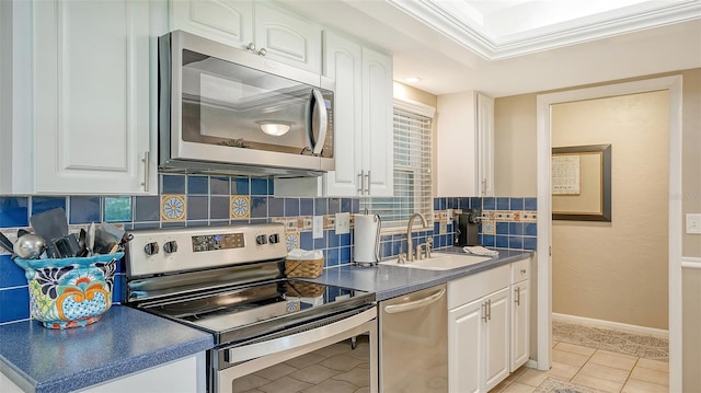 kitchen with appliances with stainless steel finishes, tasteful backsplash, sink, white cabinets, and light tile patterned floors