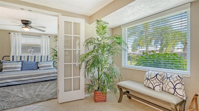 doorway to outside featuring a healthy amount of sunlight, light tile patterned floors, ceiling fan, and french doors