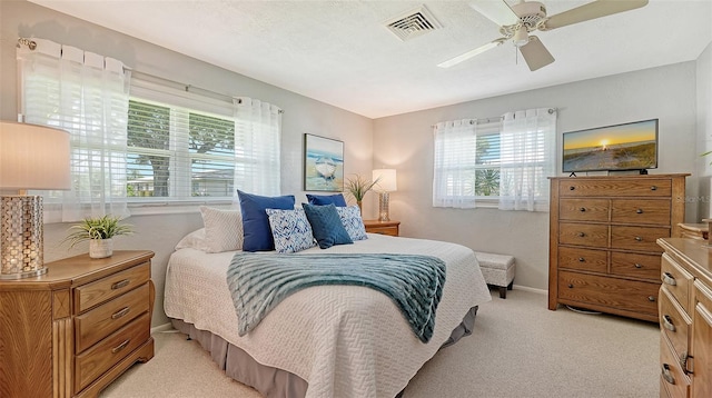 bedroom featuring multiple windows, light colored carpet, and ceiling fan