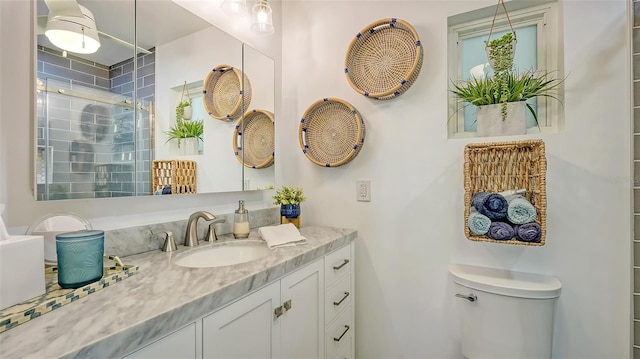 bathroom featuring vanity, an enclosed shower, and toilet