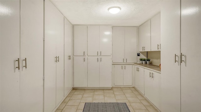 interior space with white cabinetry, a textured ceiling, and light tile patterned flooring