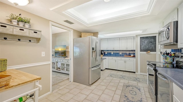 kitchen with white cabinetry, appliances with stainless steel finishes, a tray ceiling, and decorative backsplash