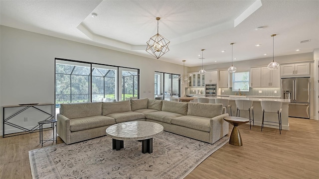 living room with light hardwood / wood-style flooring, sink, and a notable chandelier