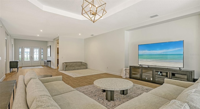 living room featuring french doors, a chandelier, and light hardwood / wood-style floors