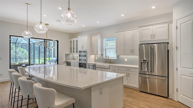 kitchen with a wealth of natural light, light hardwood / wood-style flooring, stainless steel appliances, and white cabinets