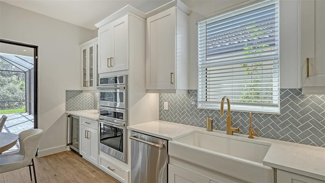 kitchen with white cabinetry, light hardwood / wood-style flooring, wine cooler, sink, and appliances with stainless steel finishes