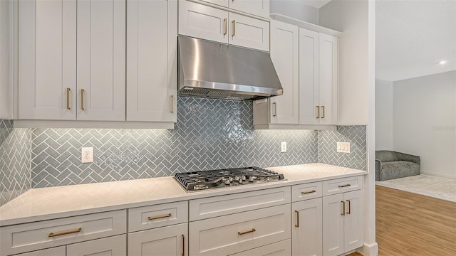 kitchen with light hardwood / wood-style flooring, stainless steel gas stovetop, white cabinets, and tasteful backsplash