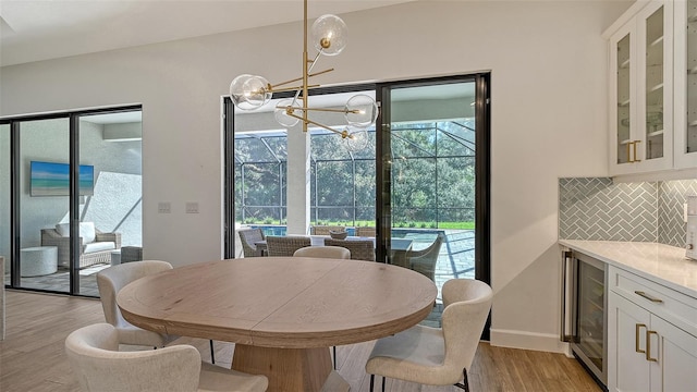 dining room featuring beverage cooler, light hardwood / wood-style floors, and a notable chandelier