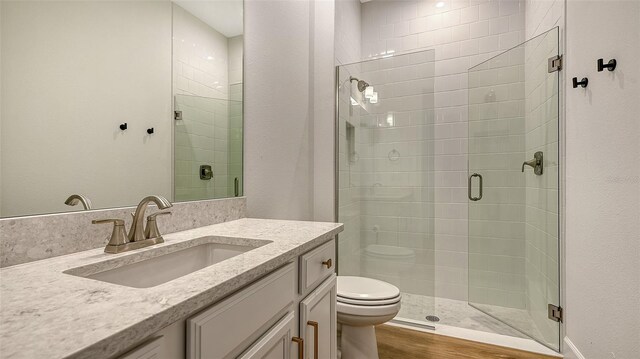 bathroom featuring a shower with shower door, wood-type flooring, toilet, and vanity