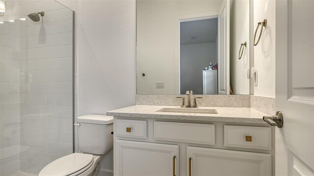 bathroom with vanity, toilet, and a tile shower