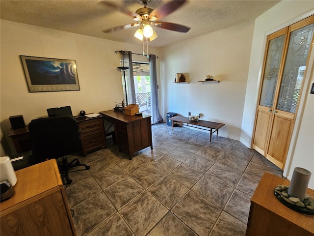 office with ceiling fan, dark tile patterned flooring, and a textured ceiling