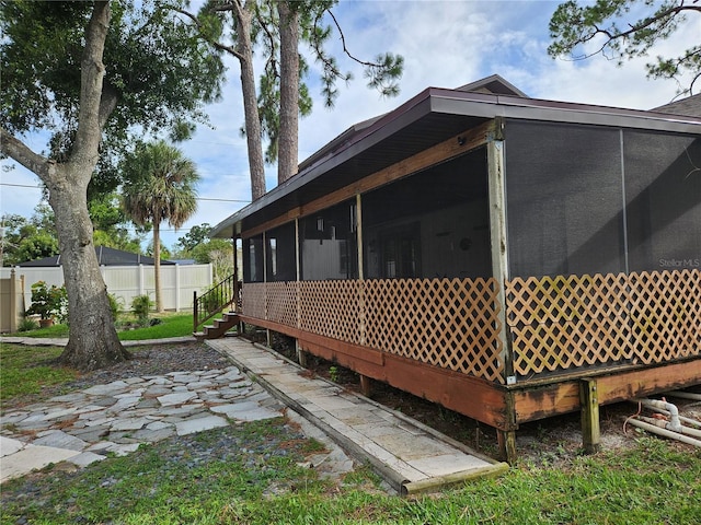 view of property exterior with a patio, fence, and a sunroom