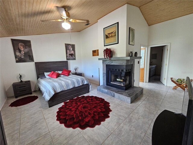 tiled bedroom featuring a ceiling fan, a tile fireplace, vaulted ceiling, ensuite bathroom, and wooden ceiling