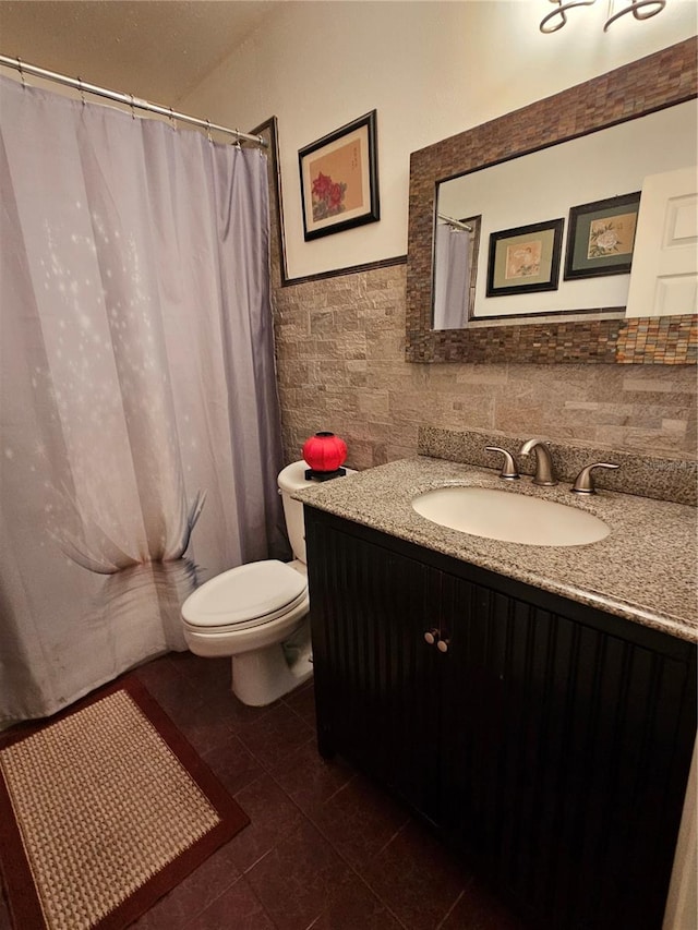 bathroom with tile walls, walk in shower, tile patterned floors, vanity, and toilet