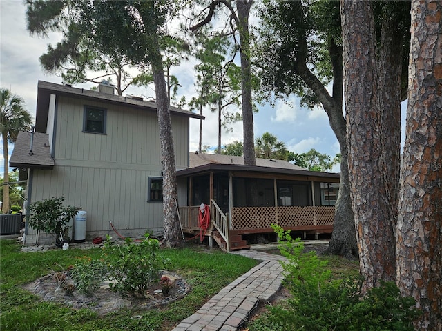 view of front of house with central AC unit and a sunroom