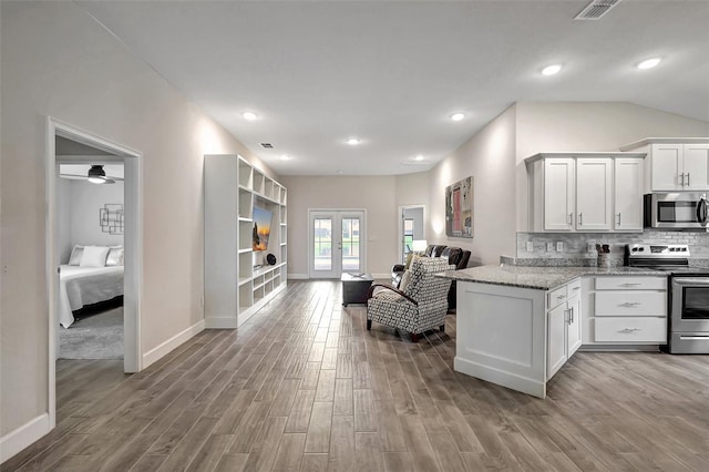 kitchen with vaulted ceiling, wood-type flooring, stainless steel appliances, ceiling fan, and white cabinets