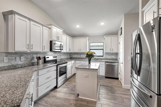 kitchen with appliances with stainless steel finishes, a center island, wood-type flooring, and white cabinetry