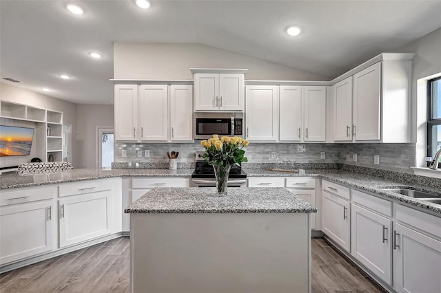 kitchen with appliances with stainless steel finishes, a center island, white cabinetry, and sink