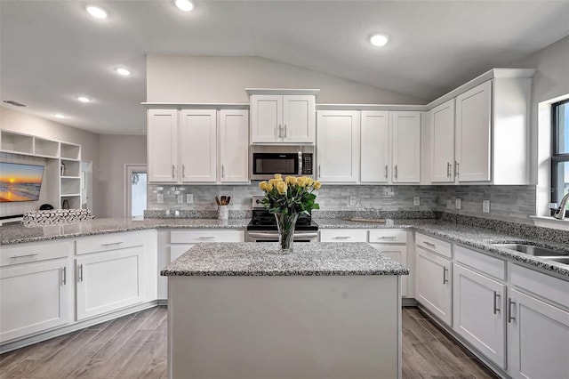 kitchen with white cabinets, appliances with stainless steel finishes, wood finish floors, and a sink