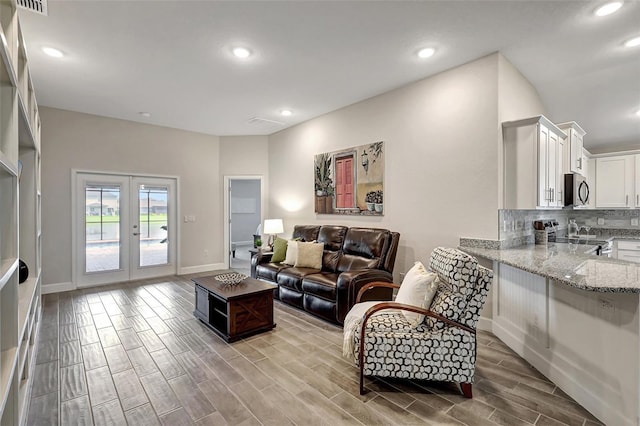 living area featuring wood finish floors, visible vents, recessed lighting, french doors, and baseboards