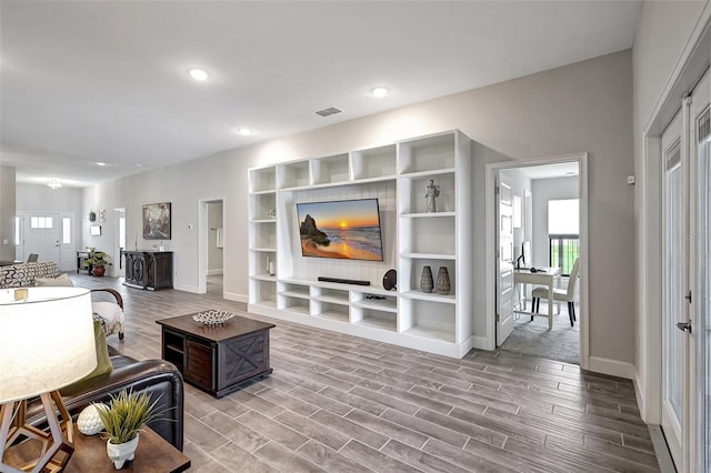 living area with recessed lighting, wood finished floors, visible vents, and baseboards