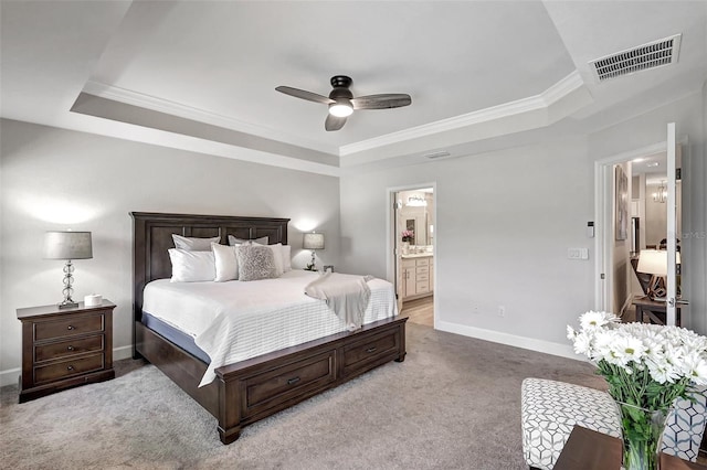 bedroom featuring a raised ceiling, ceiling fan, carpet, and connected bathroom