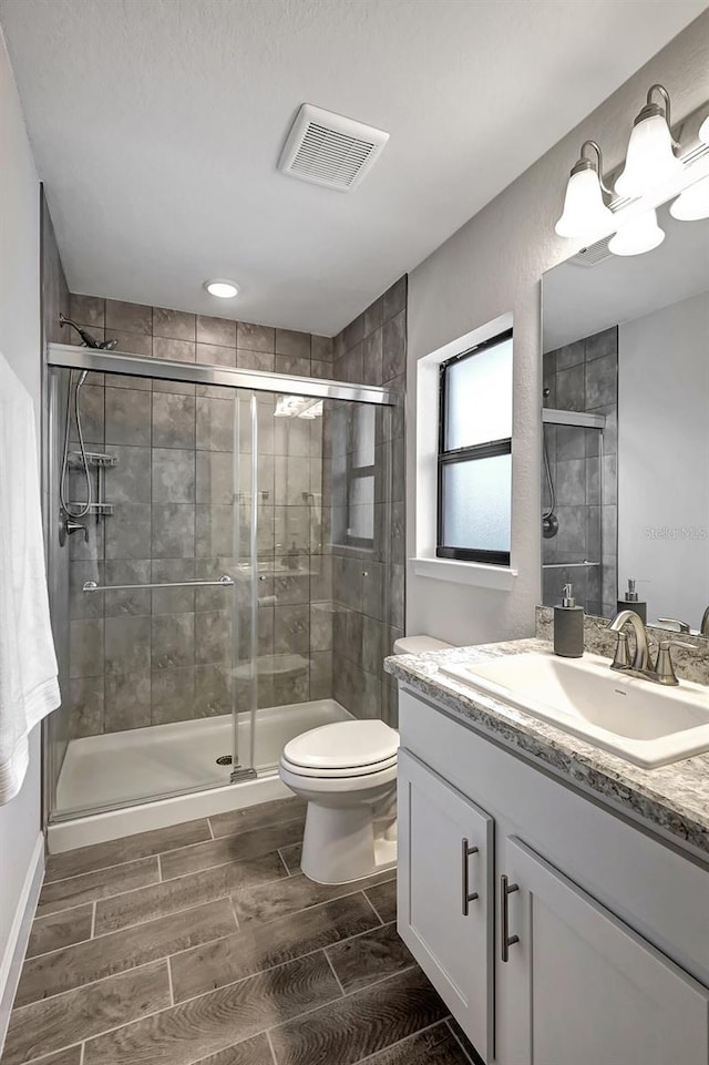 bathroom featuring vanity, toilet, and a shower with door