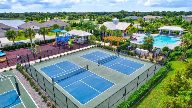 view of tennis court with a community pool and a playground