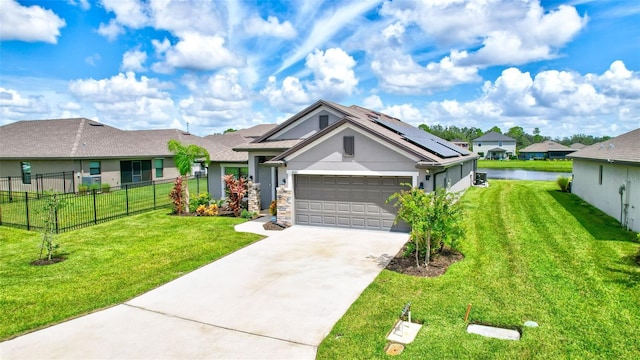 ranch-style home featuring a garage, a water view, a front lawn, and solar panels