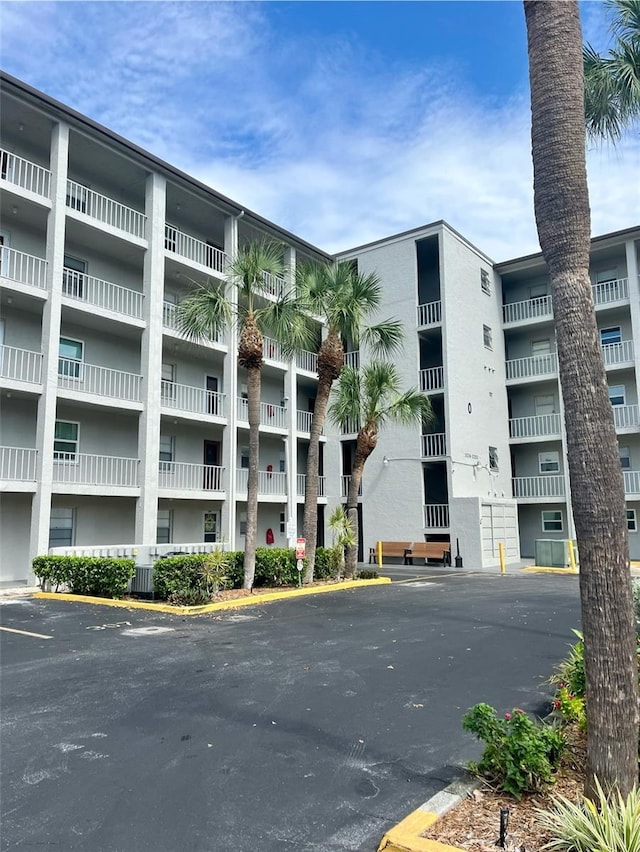 view of property featuring uncovered parking and cooling unit