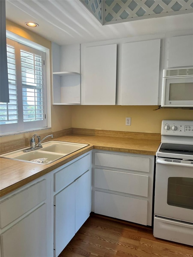 kitchen with white cabinets, light countertops, a sink, and white appliances