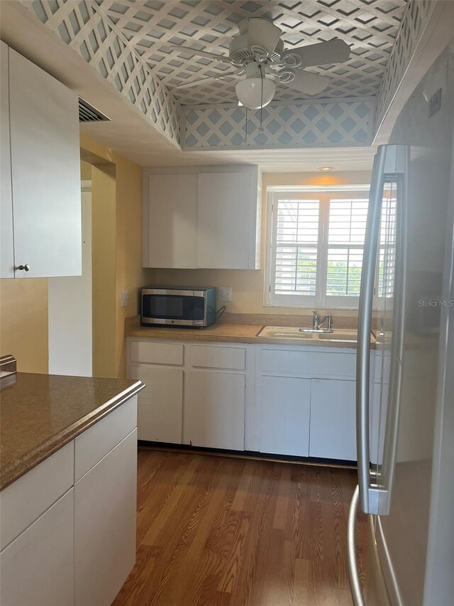 kitchen featuring fridge, ceiling fan, stainless steel microwave, white cabinetry, and dark wood-type flooring