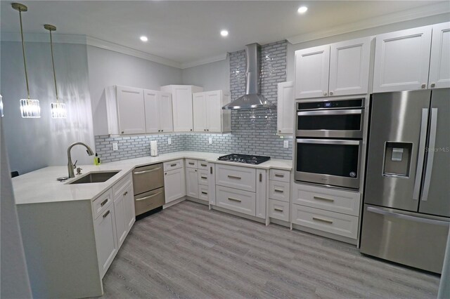 kitchen with light wood-type flooring, sink, wall chimney exhaust hood, appliances with stainless steel finishes, and white cabinets