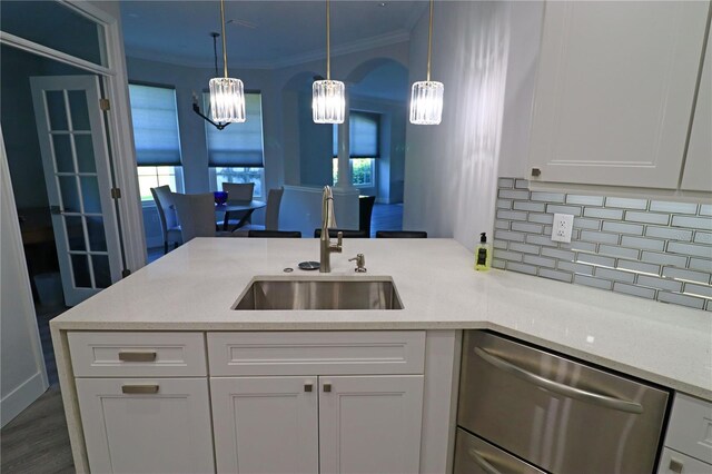 kitchen featuring crown molding, decorative light fixtures, dishwasher, sink, and white cabinets