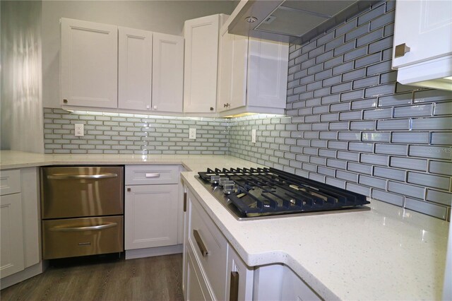 kitchen with white cabinets, stainless steel gas stovetop, light stone countertops, dark wood-type flooring, and tasteful backsplash