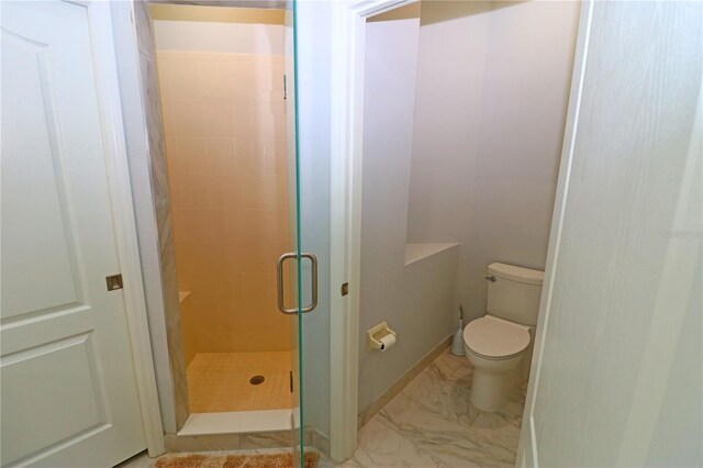 bathroom featuring a shower with shower door and toilet