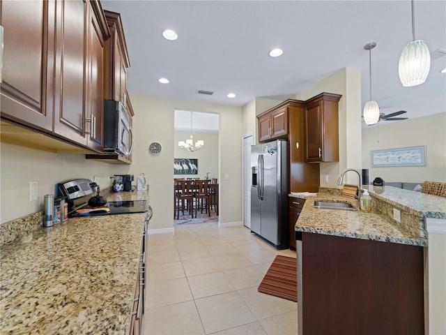 kitchen featuring light stone countertops, appliances with stainless steel finishes, kitchen peninsula, sink, and pendant lighting